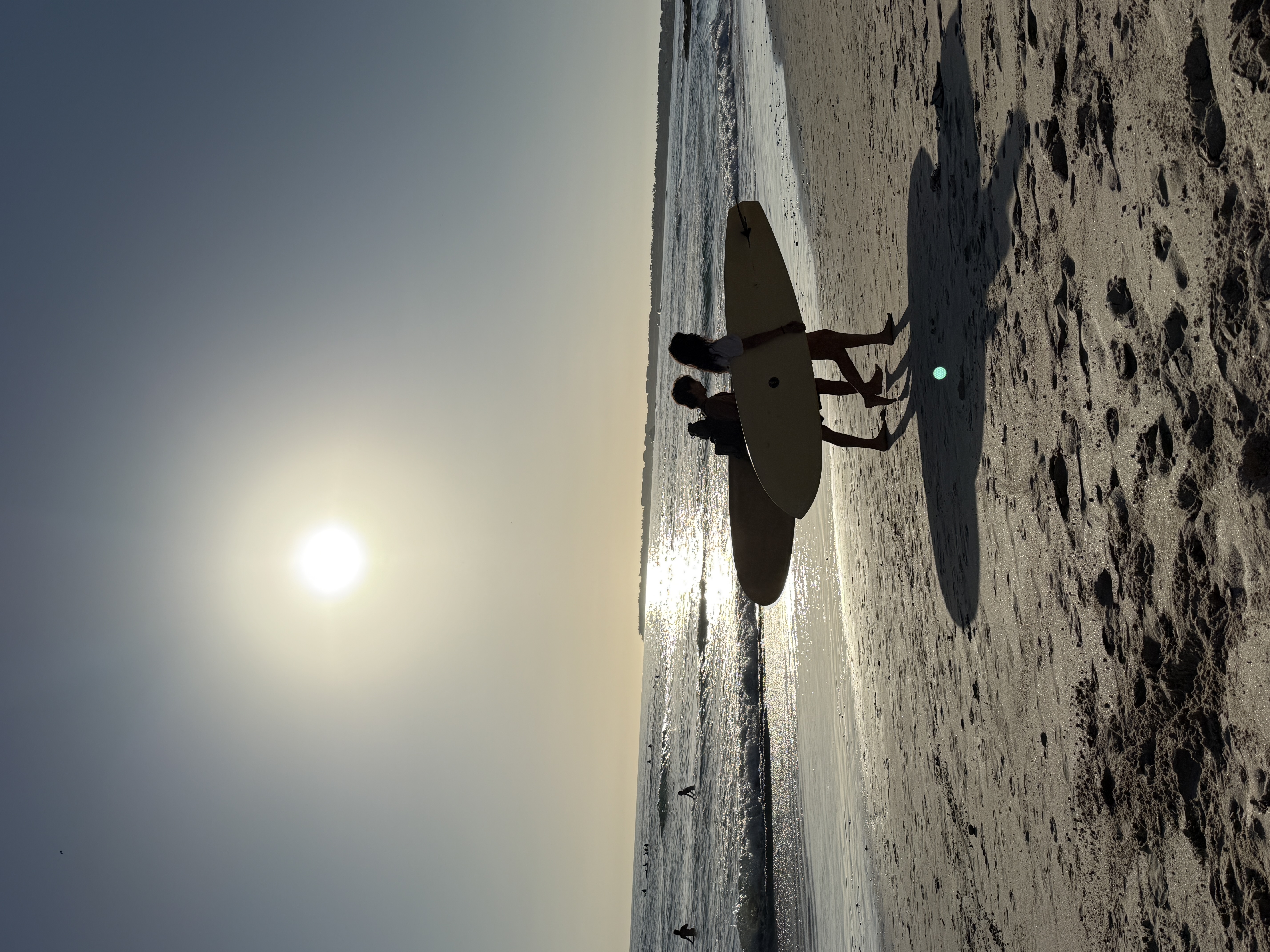 Surfers walking the beach at sunset near Ola Mita